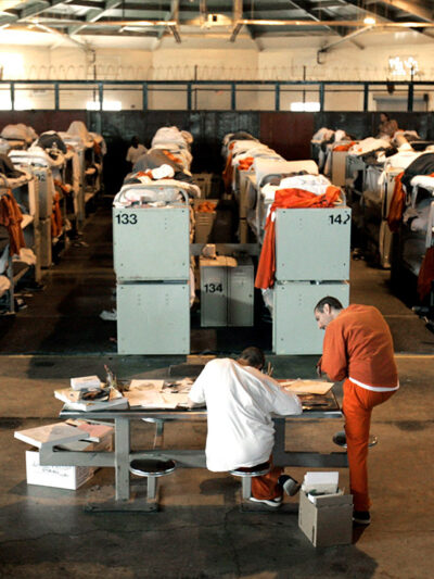 People in prison housed in a room with three-tiered bunk beds.