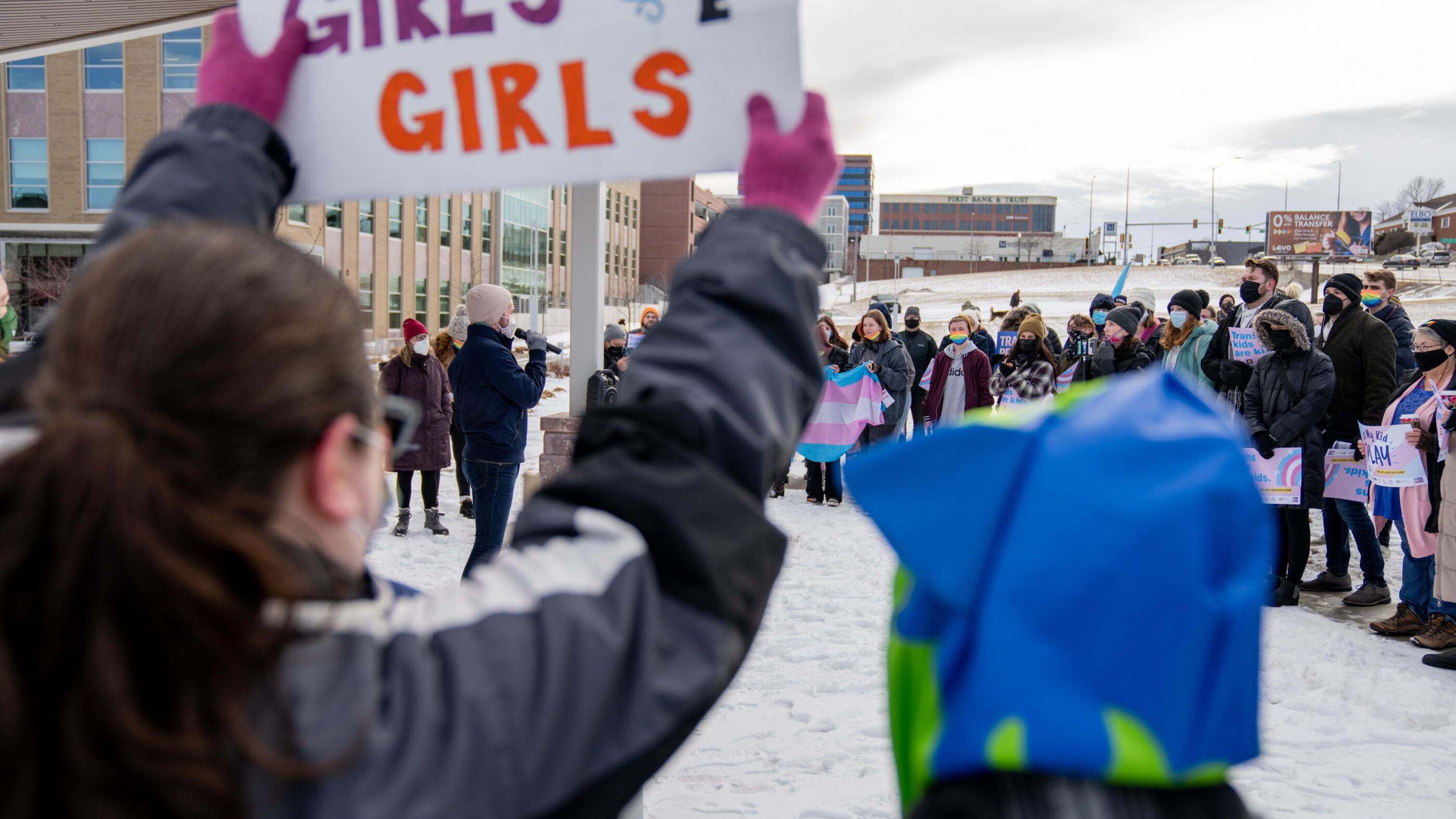 Image of someone holding a sign that says, "Trans girls are girls."