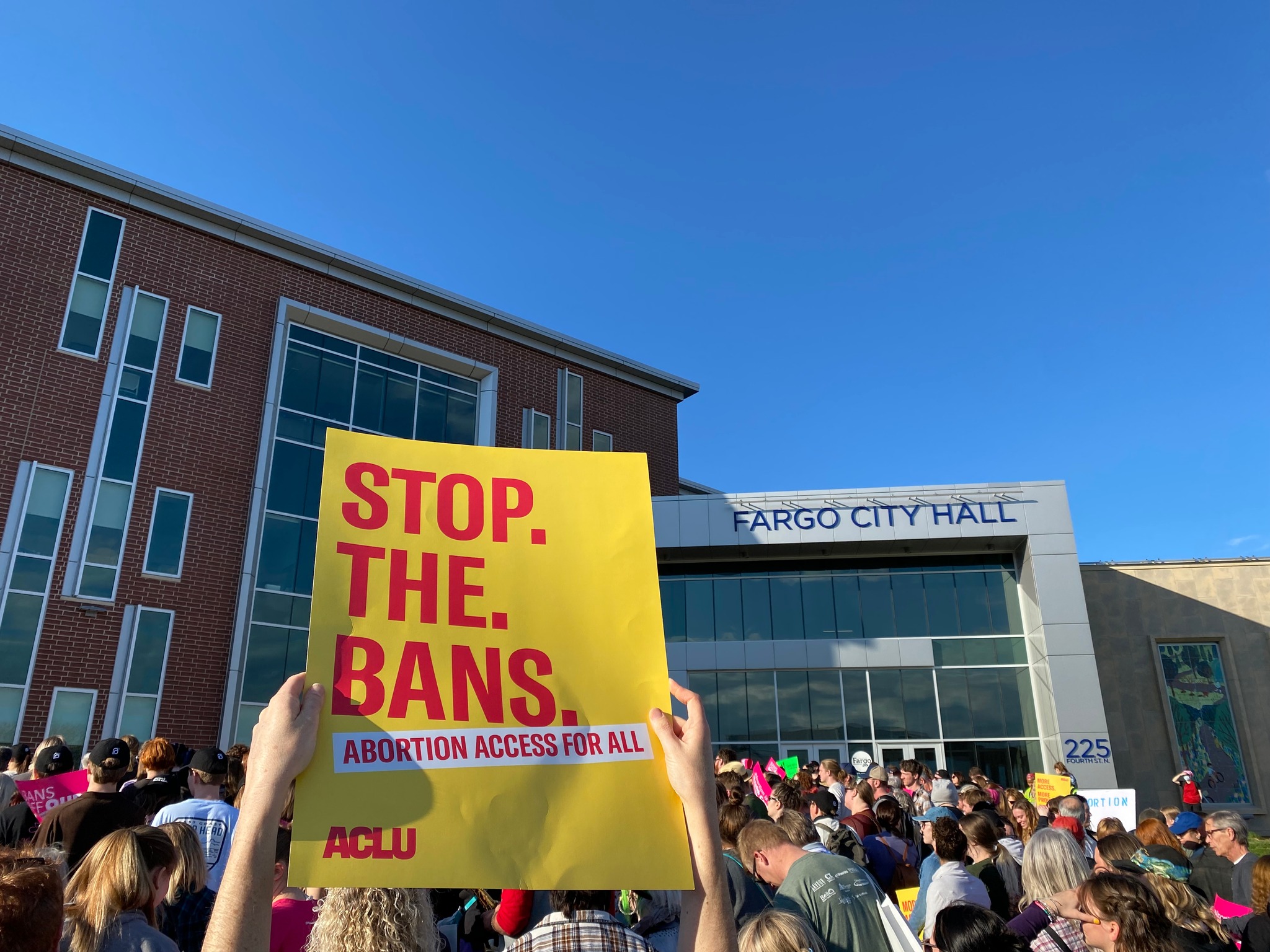 Image of a protest sign being held up by someone that reads, "stop. the. bans. abortion access for all."
