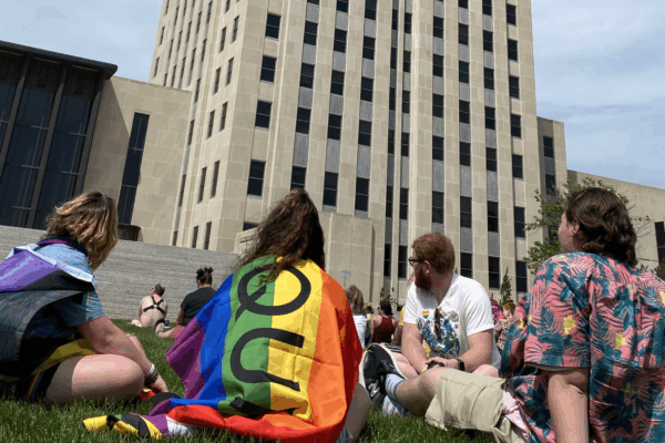 Image of people sitting on grass, one has a pride flag