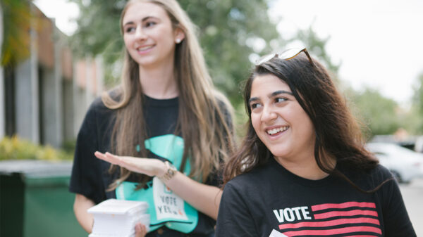 Two smiling canvassers carrying voting information.