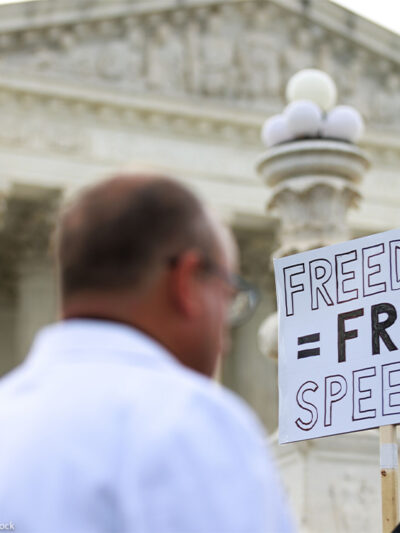 Free Speech supporters hold up a sign reading "FREEDOM = FREE SPEECH" outside the U.S. Supreme Court.