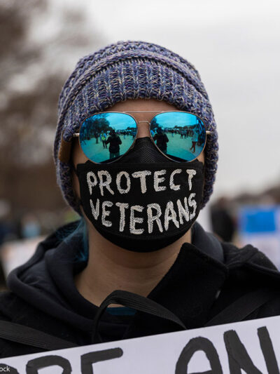 A demonstrator wears a mask with the text ''Protect Veterans'' during the ''Veterans March'' at the National Mall in Washington.