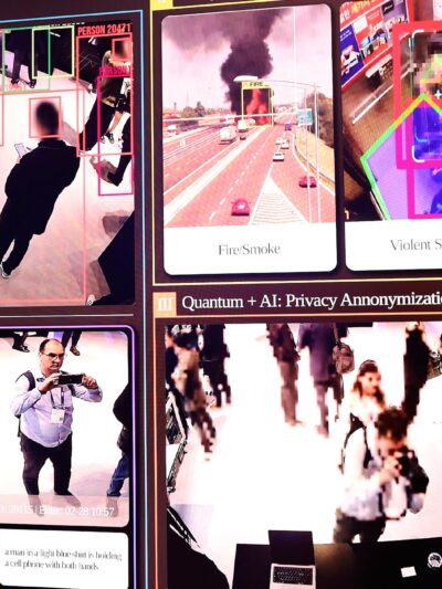 Large display showing an AI security surveillance dashboard using facial recognition-style tracking, with colored boxes around people in CCTV footage and labeled panels for "Advanced Search/Alarm," "Anomaly Analytics" (fire/smoke, violent situation, fall detection), and "Privacy Anonymization."