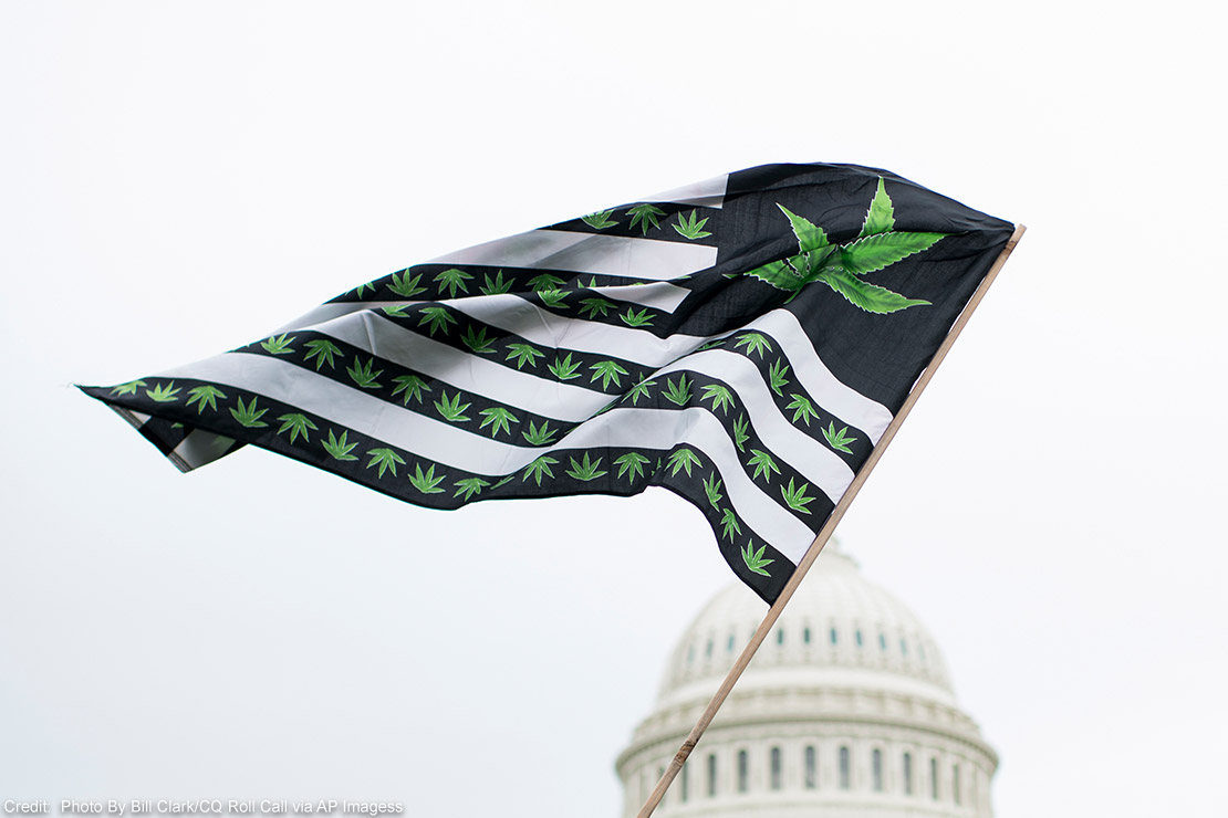 A U.S. flag redesigned with cannabis leaves blows in the wind in front of the U.S. Capitol.