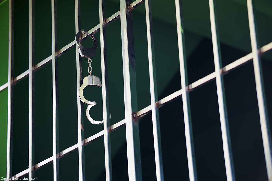 Handcuffs hanging from jail cell.