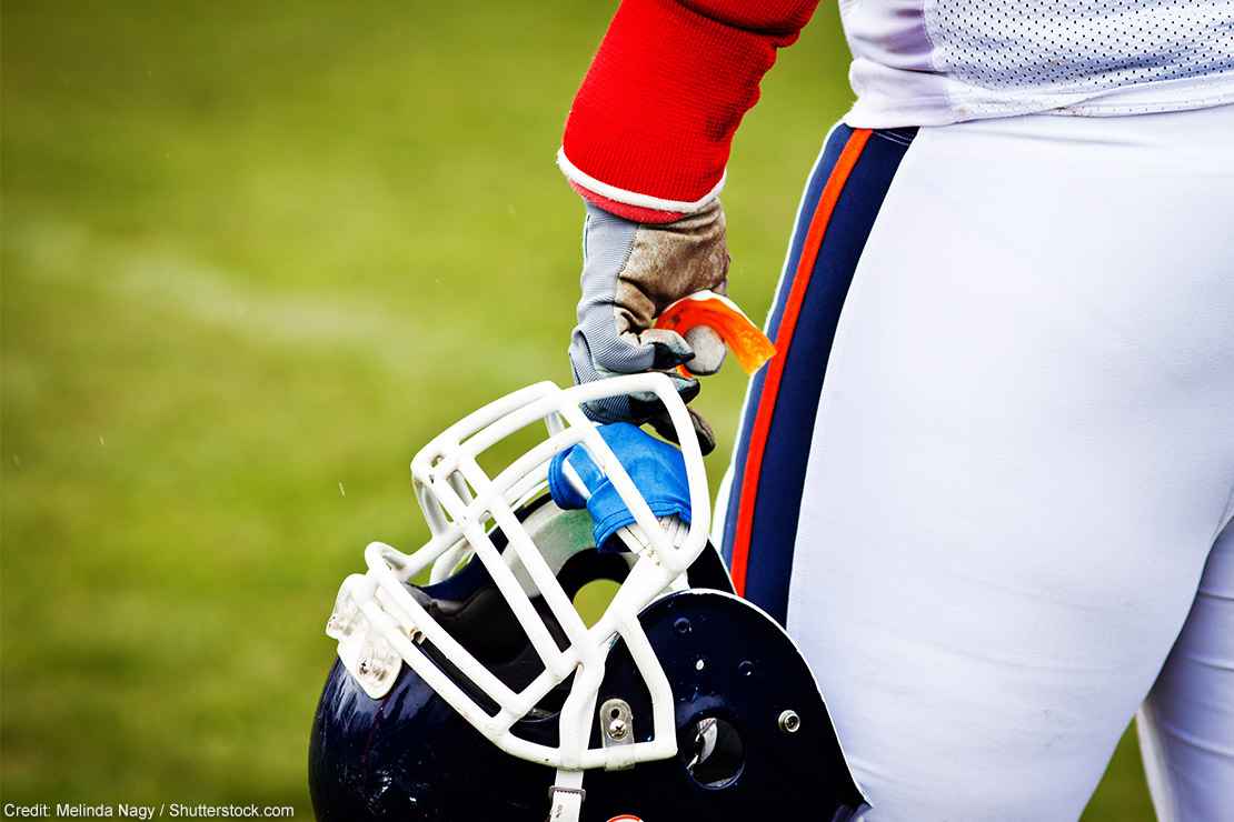A football helmet in a player's hand.