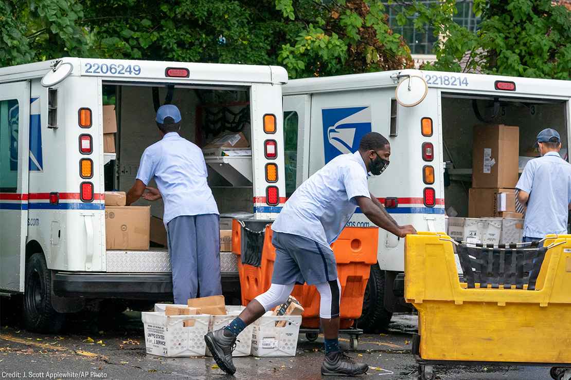 Letter carriers load mail trucks for deliveries at a U.S. Postal Service facility.